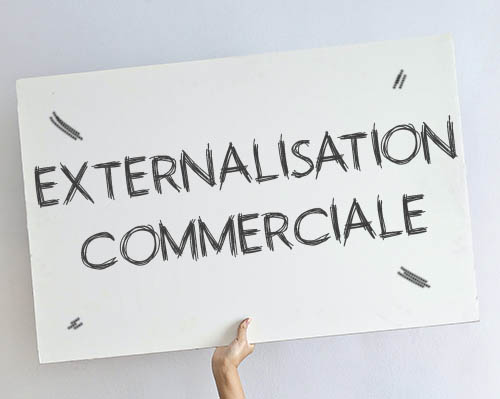 Personne tenant un tableau avec écrit Externalisation Commerciale